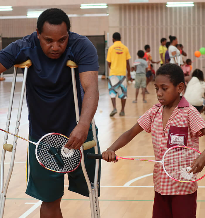Disabled man playing badminton with child
