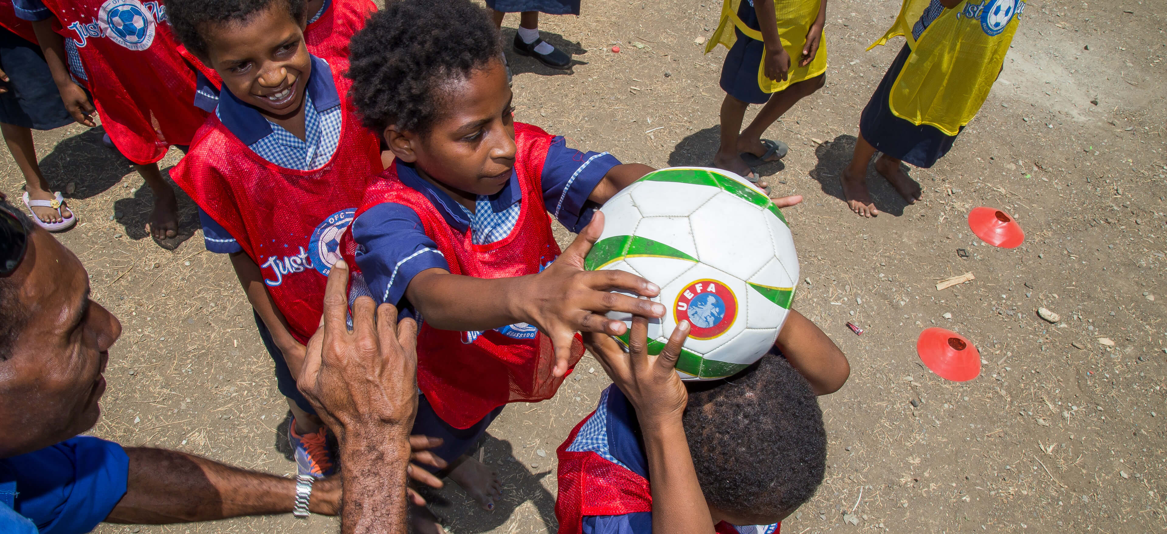 Small children pass a football over their heads