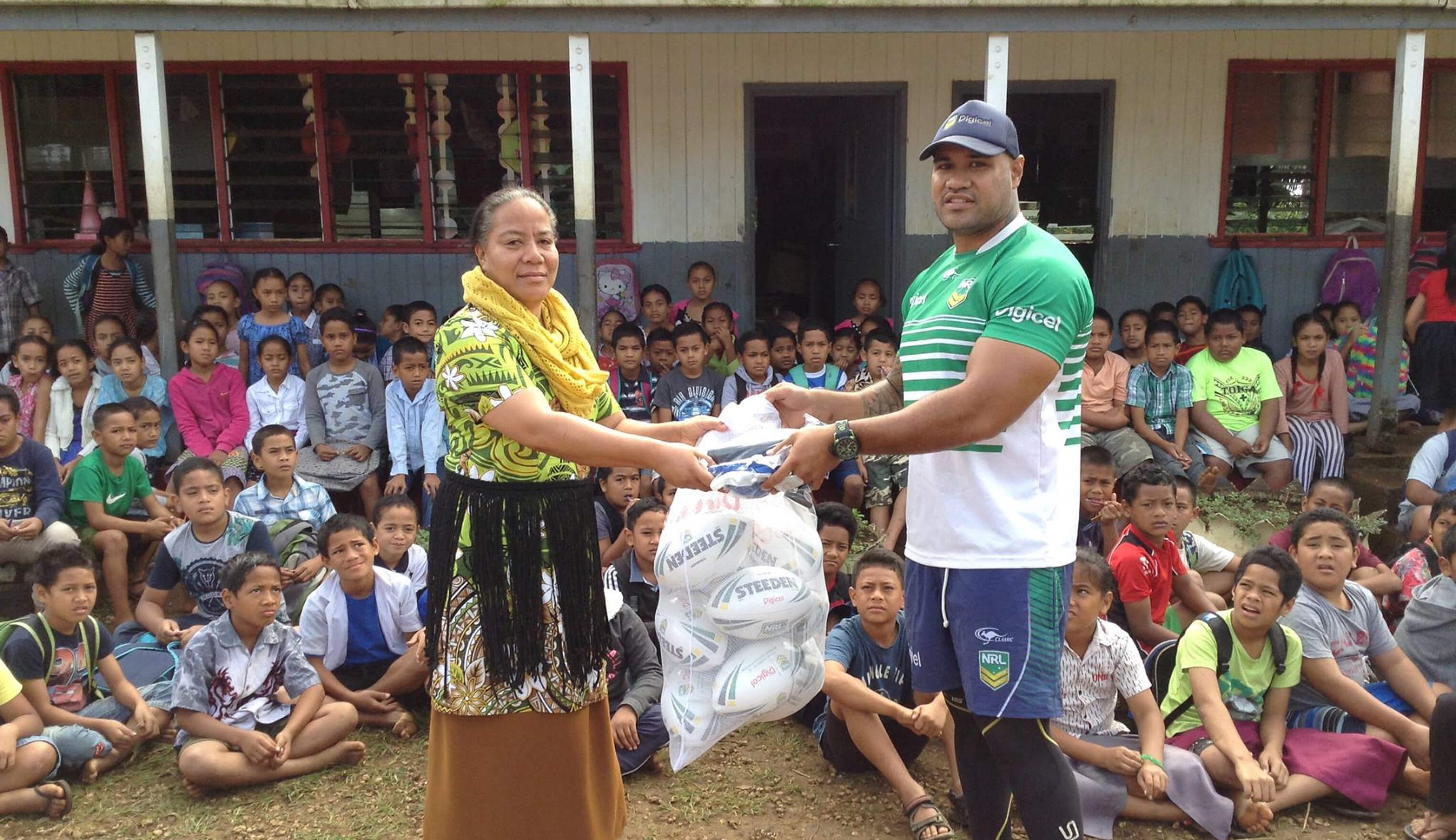 Young children wait for volunteer leaders to pass out rugby league footballs