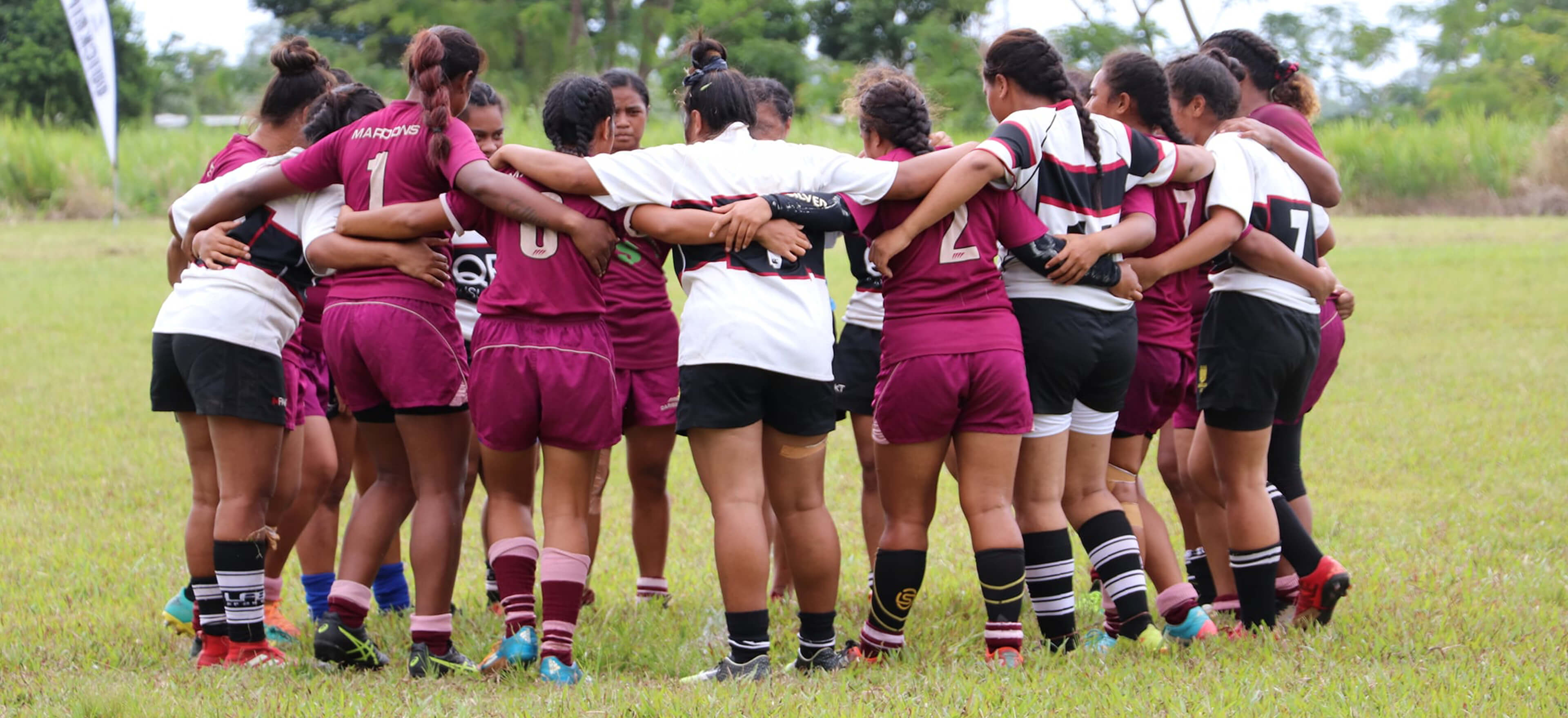 Young female rugby players with their arms around each other