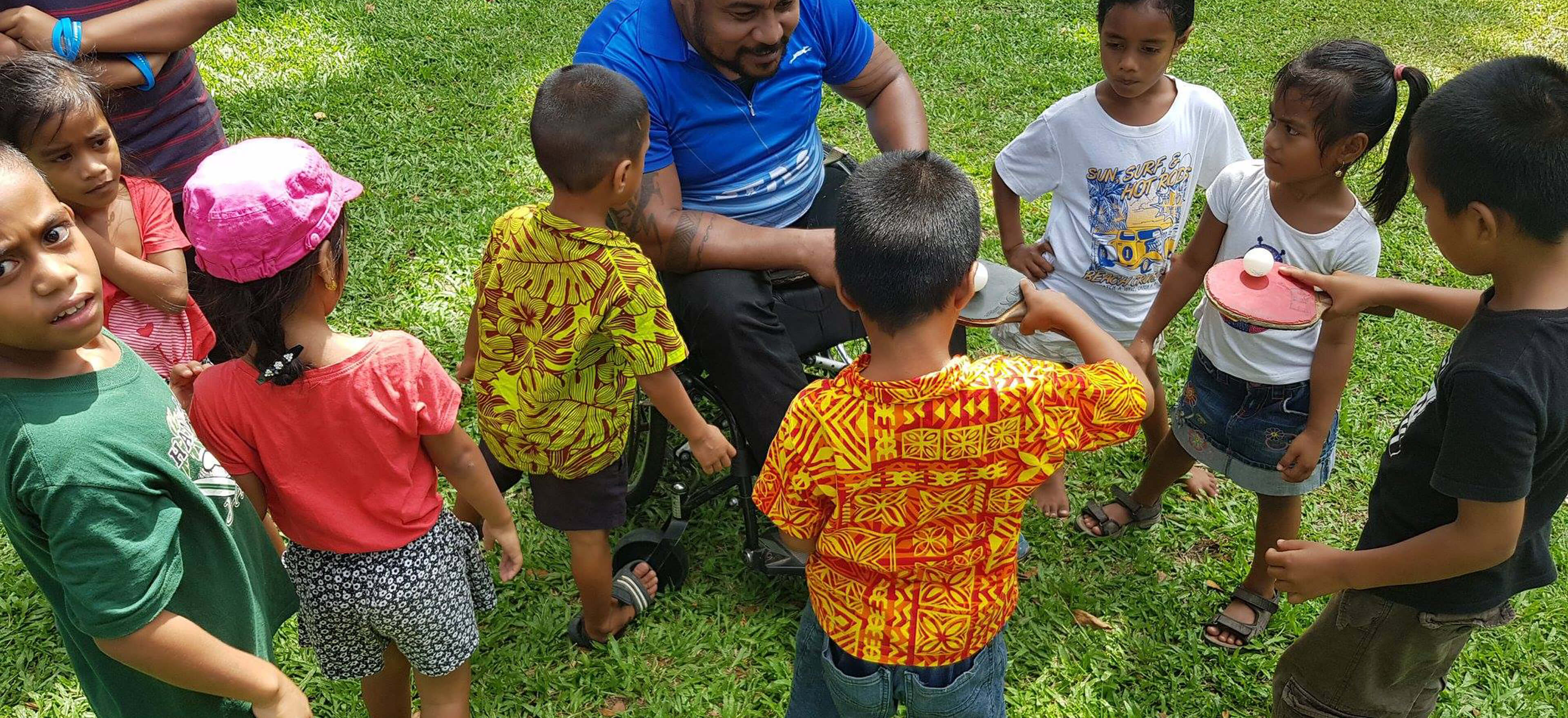 Volunteer teaching young people how to play tennis table