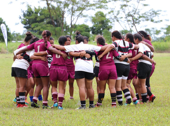 Young female rugby players with their arms around each other 