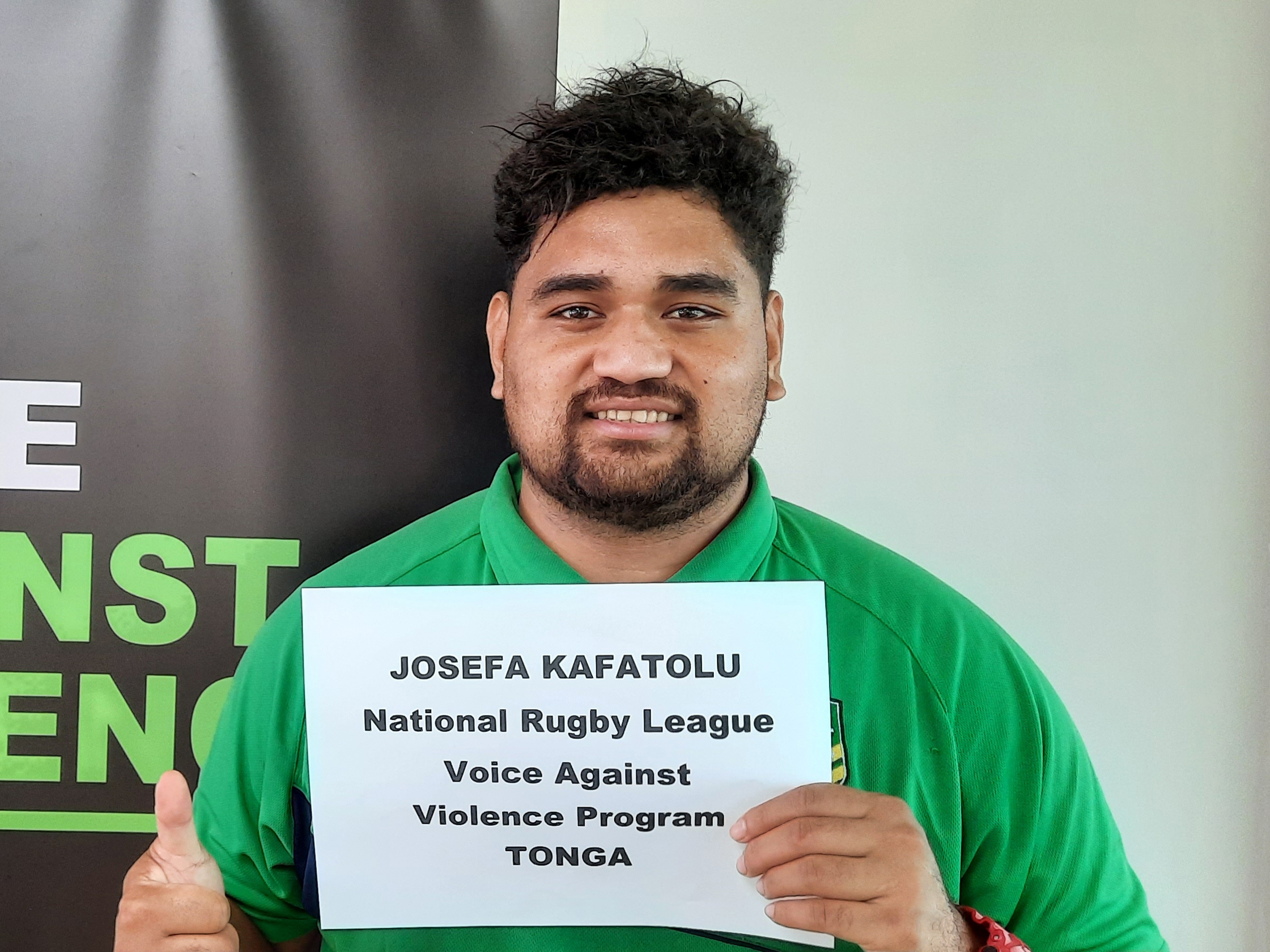 Man in Tonga holding a sign showing his name and job title