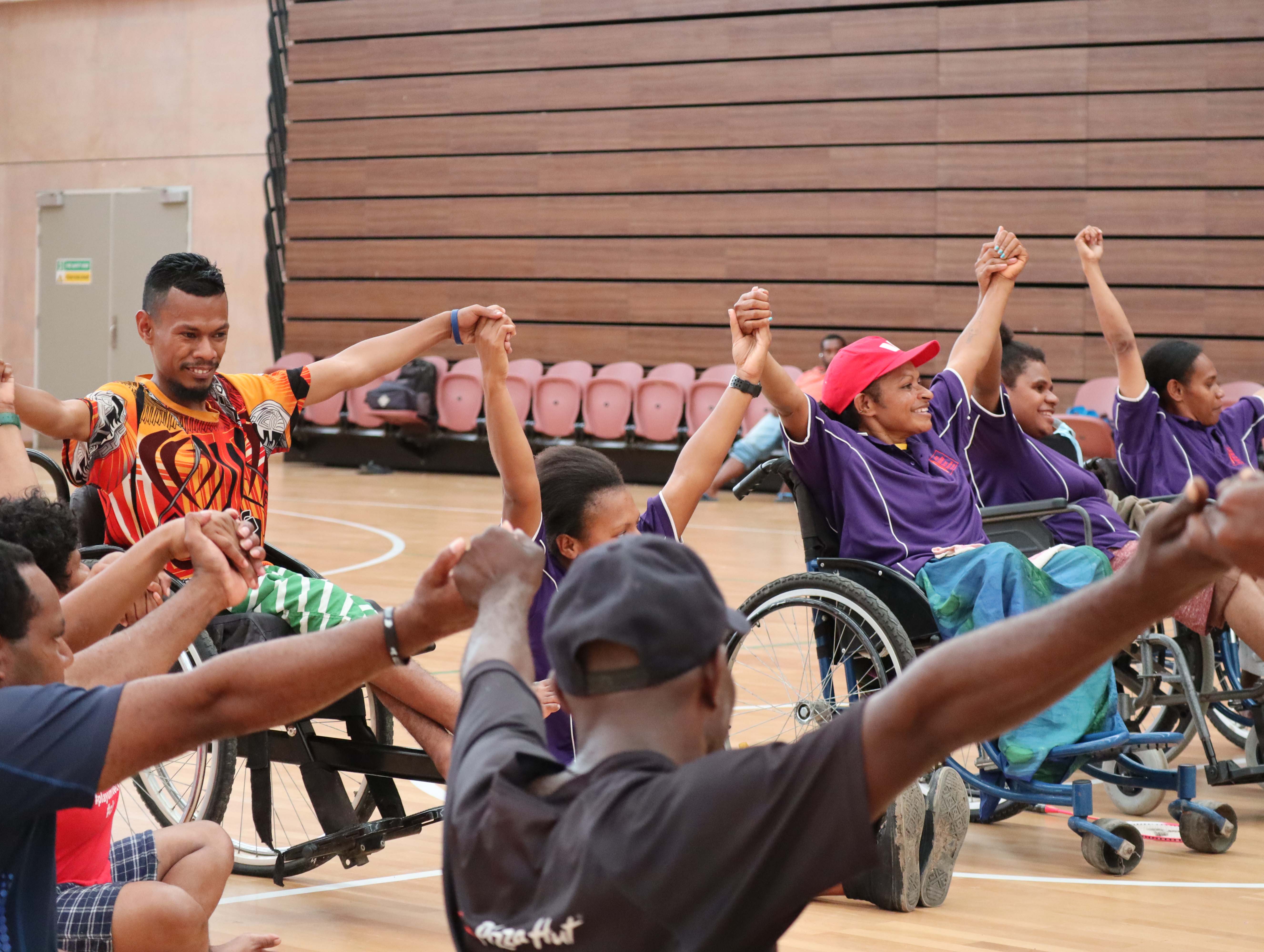 People in wheelchairs in Papua New Guinea holding hands 