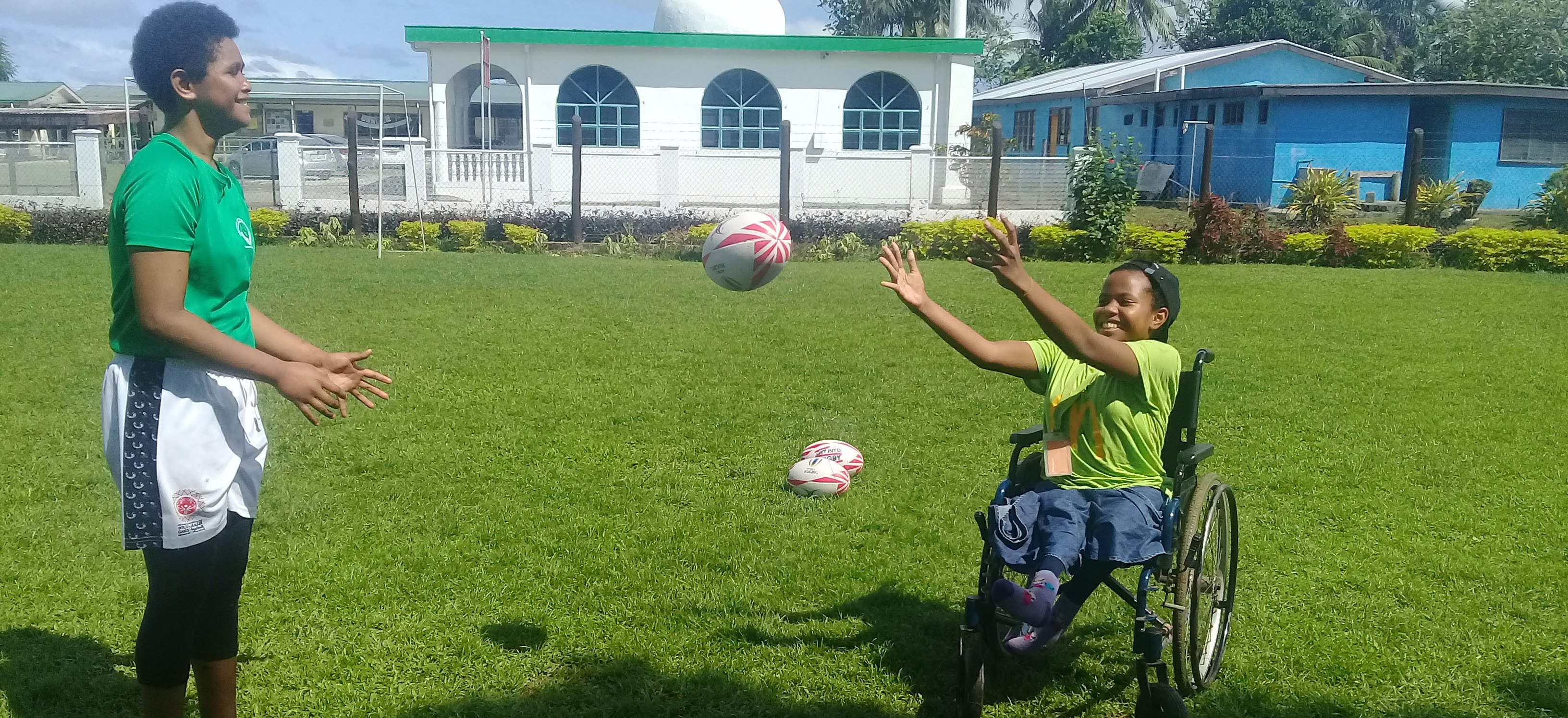 A girl in a wheelchair in Fiji passing a rugby ball