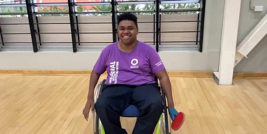 A Fijian man in a wheelchair holding a table tennis bat 