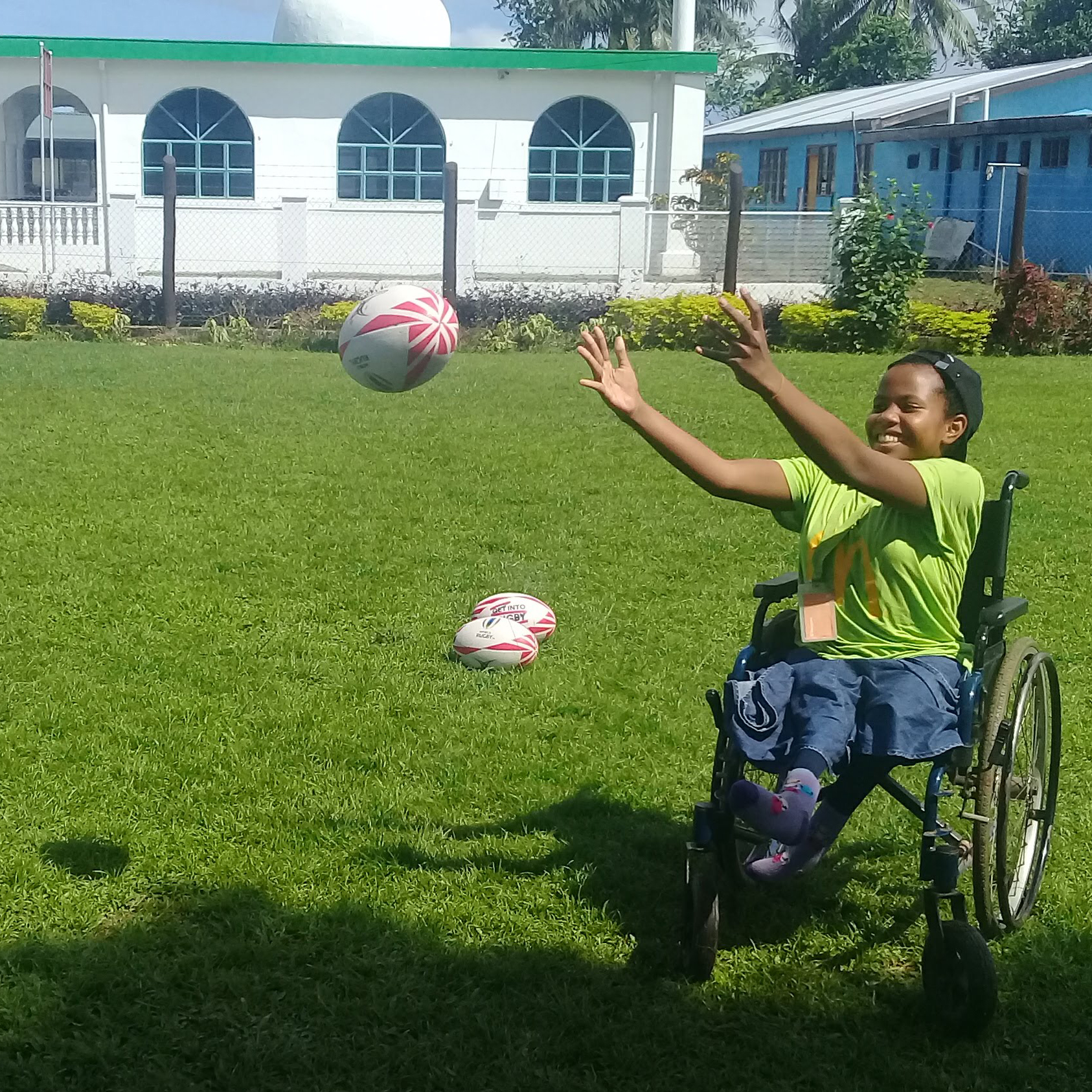 A girl in a wheelchair in Fiji passing a rugby ball