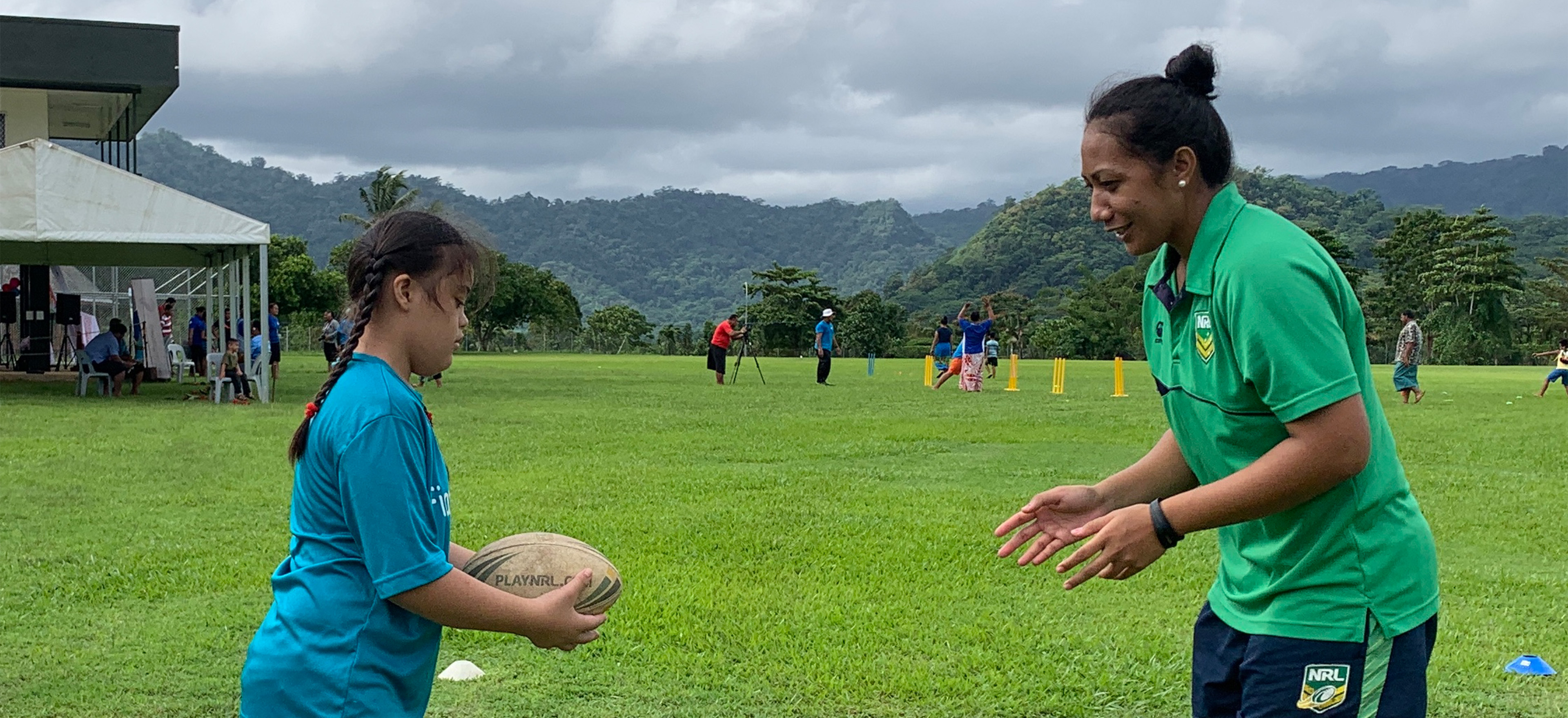 A girl is about to pass a rugby ball to a lady who is ready to catch it