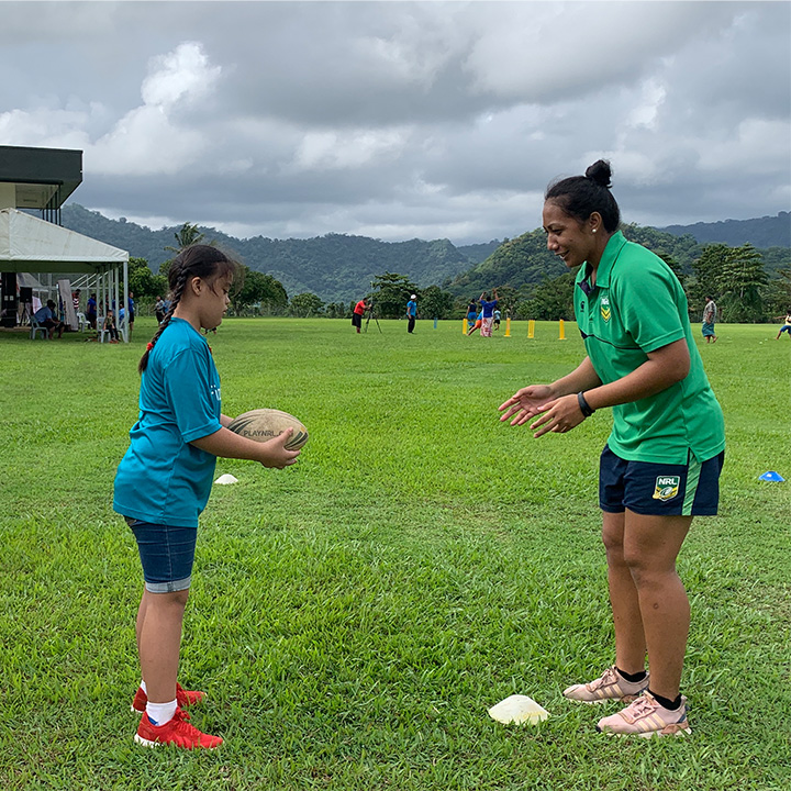 A girl is about to pass a rugby ball to a woman who is ready to catch it