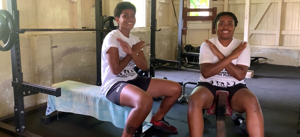 Women in Fiji cross their arms to show the International Women's Day gesture
