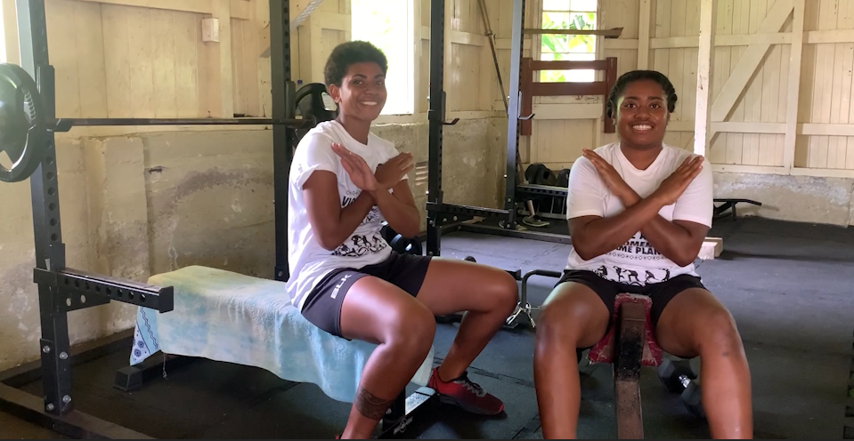 Women in Fiji cross their arms to show the International Women's Day gesture