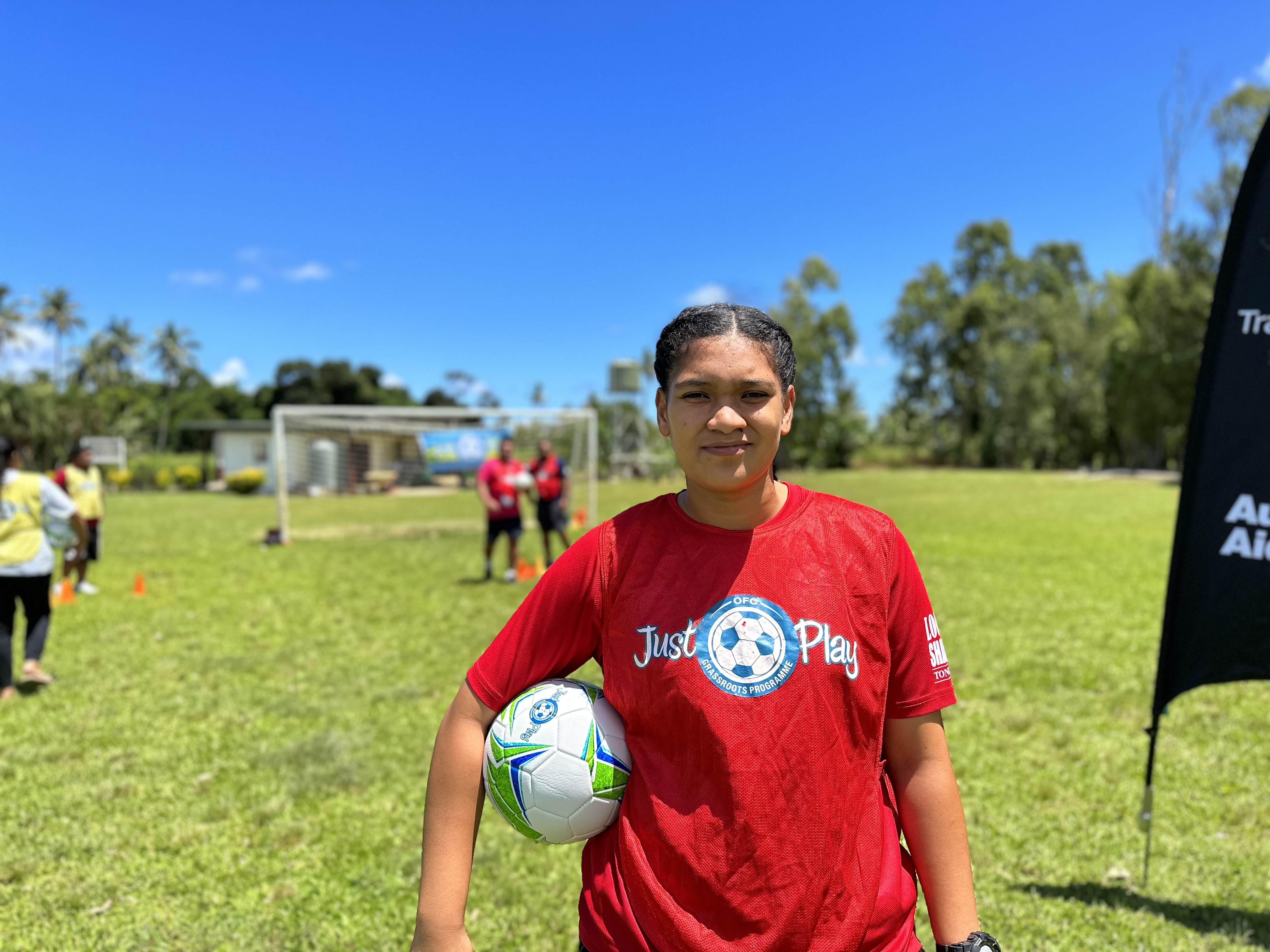 Woman in Tonga holding football against her waist while smiling