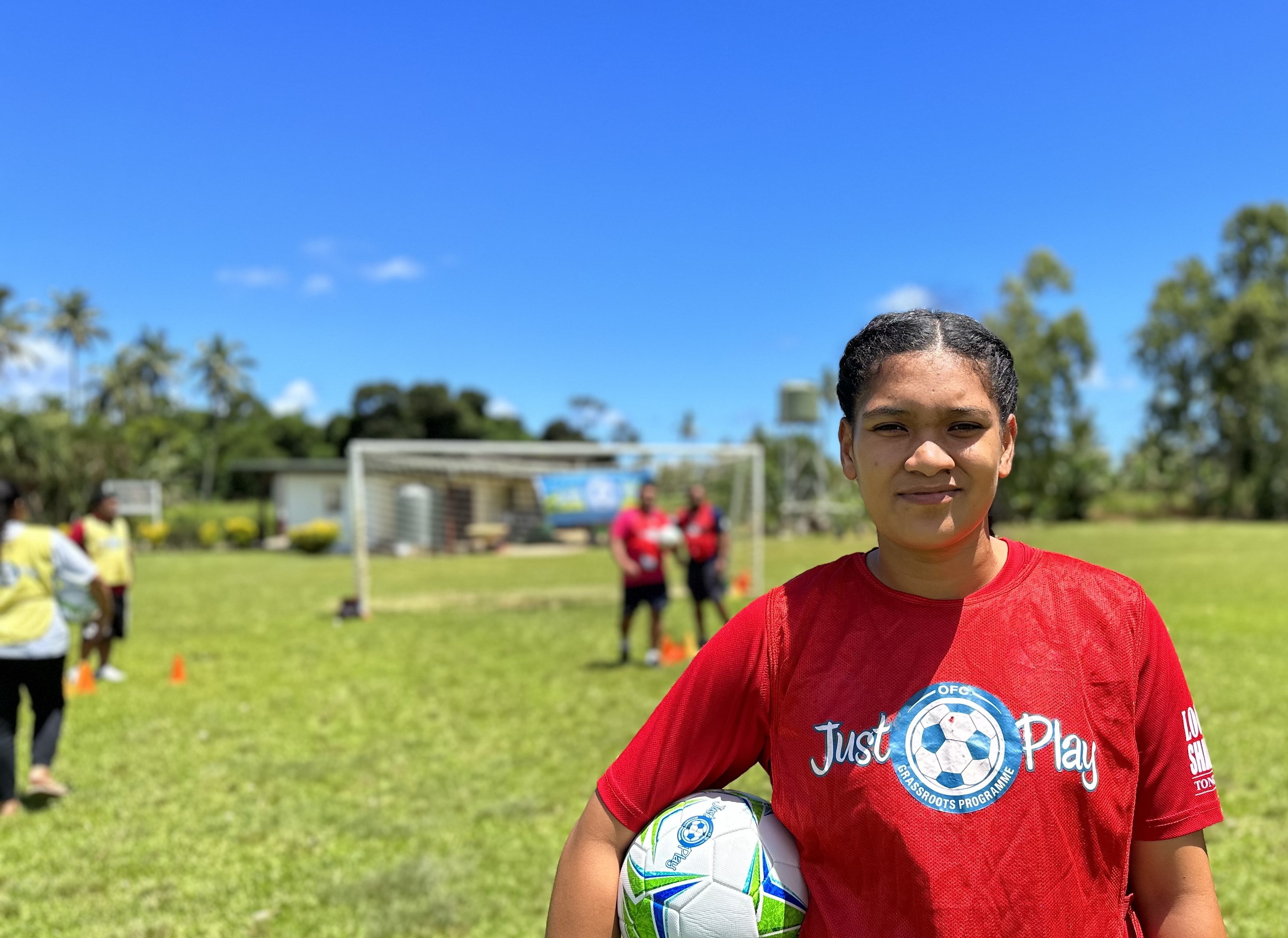 Woman in Tonga holding football against her waist while smiling