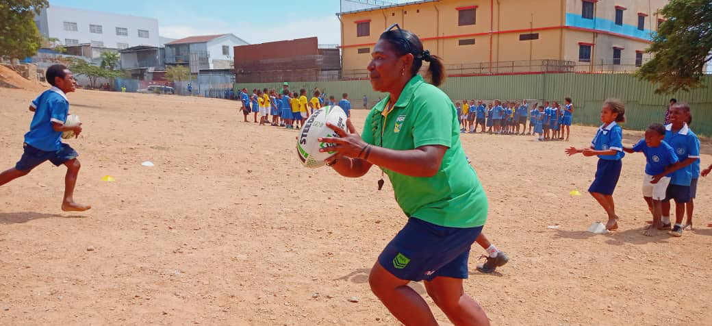 A woman running a rugby league activity in a school