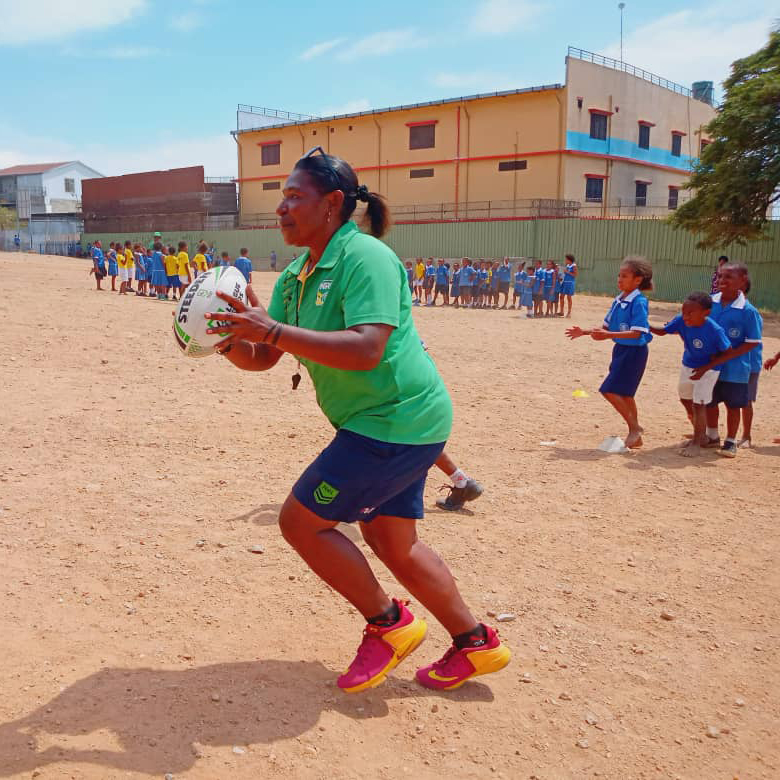 A woman running a rugby league activity in a school