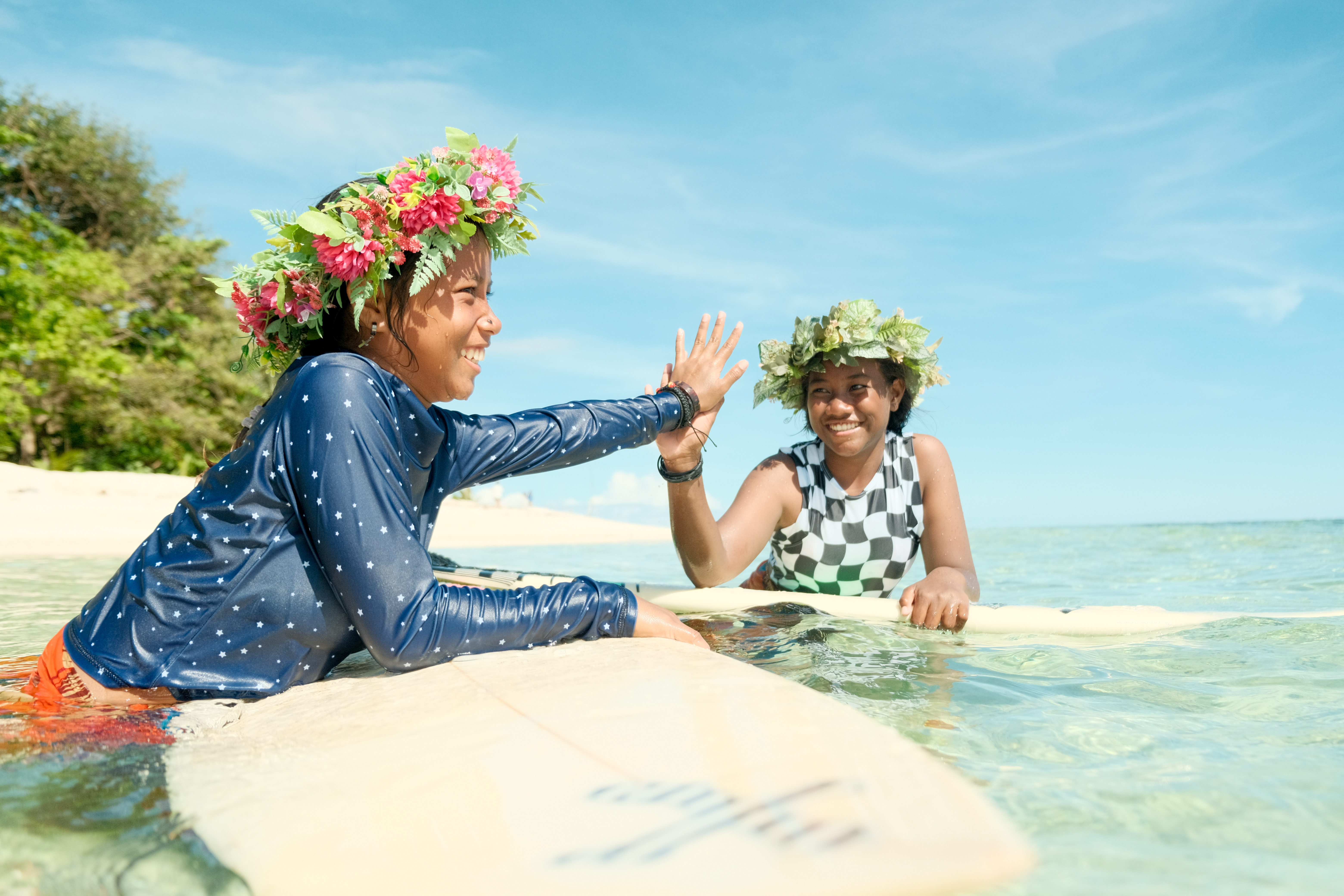 Two surfer girls Hi 5 in the water 
