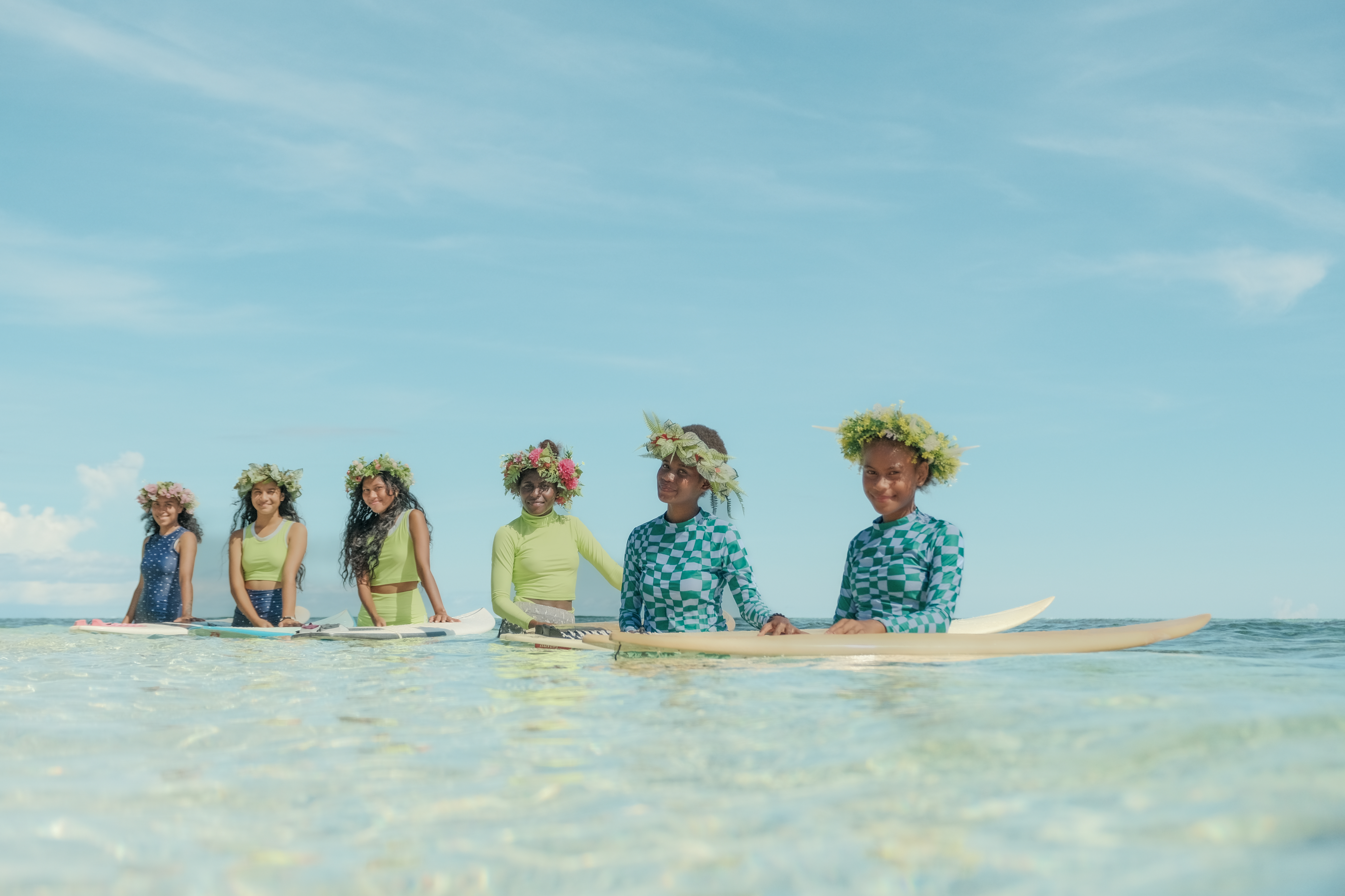 Girls sitting on surfboards in the Solomon Islands ocean 