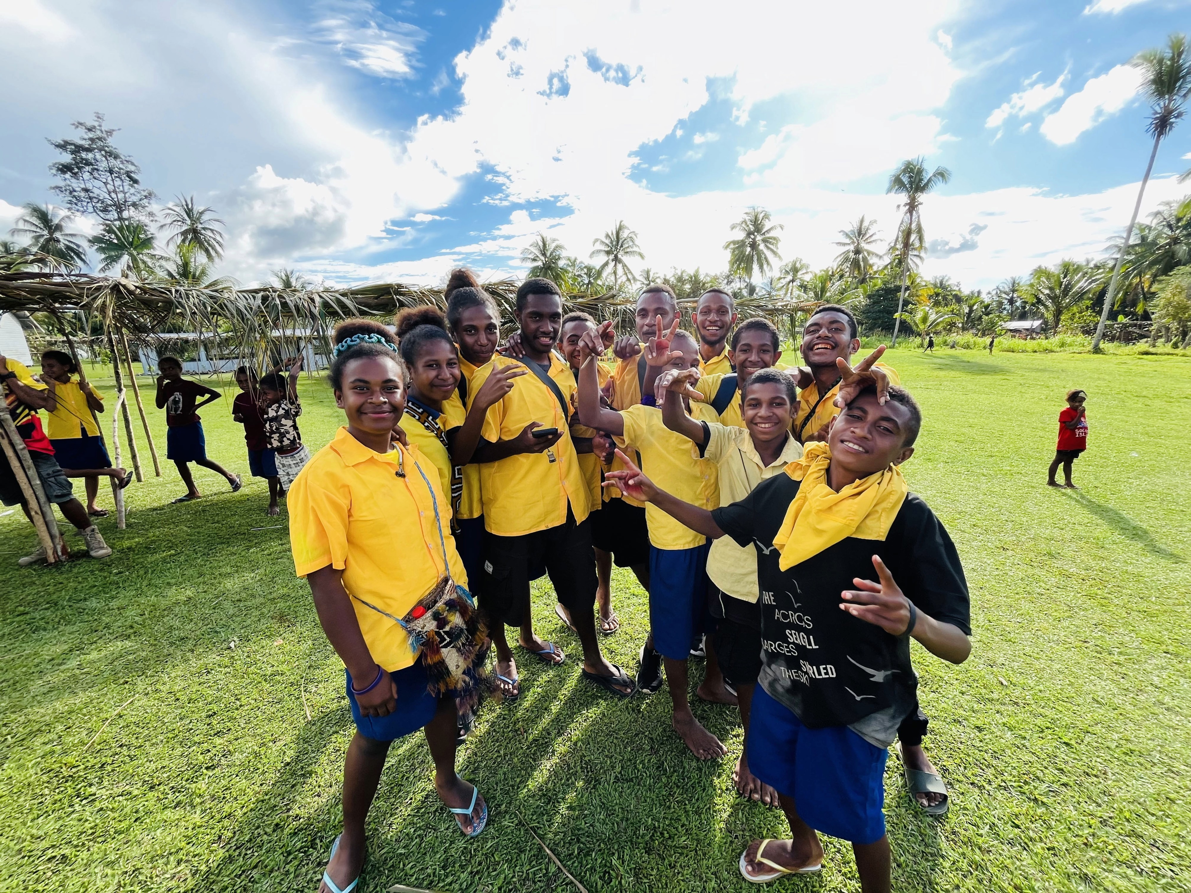 A group of K4K participants on a sports field, arms around each other's shoulders and smiling at the camera
