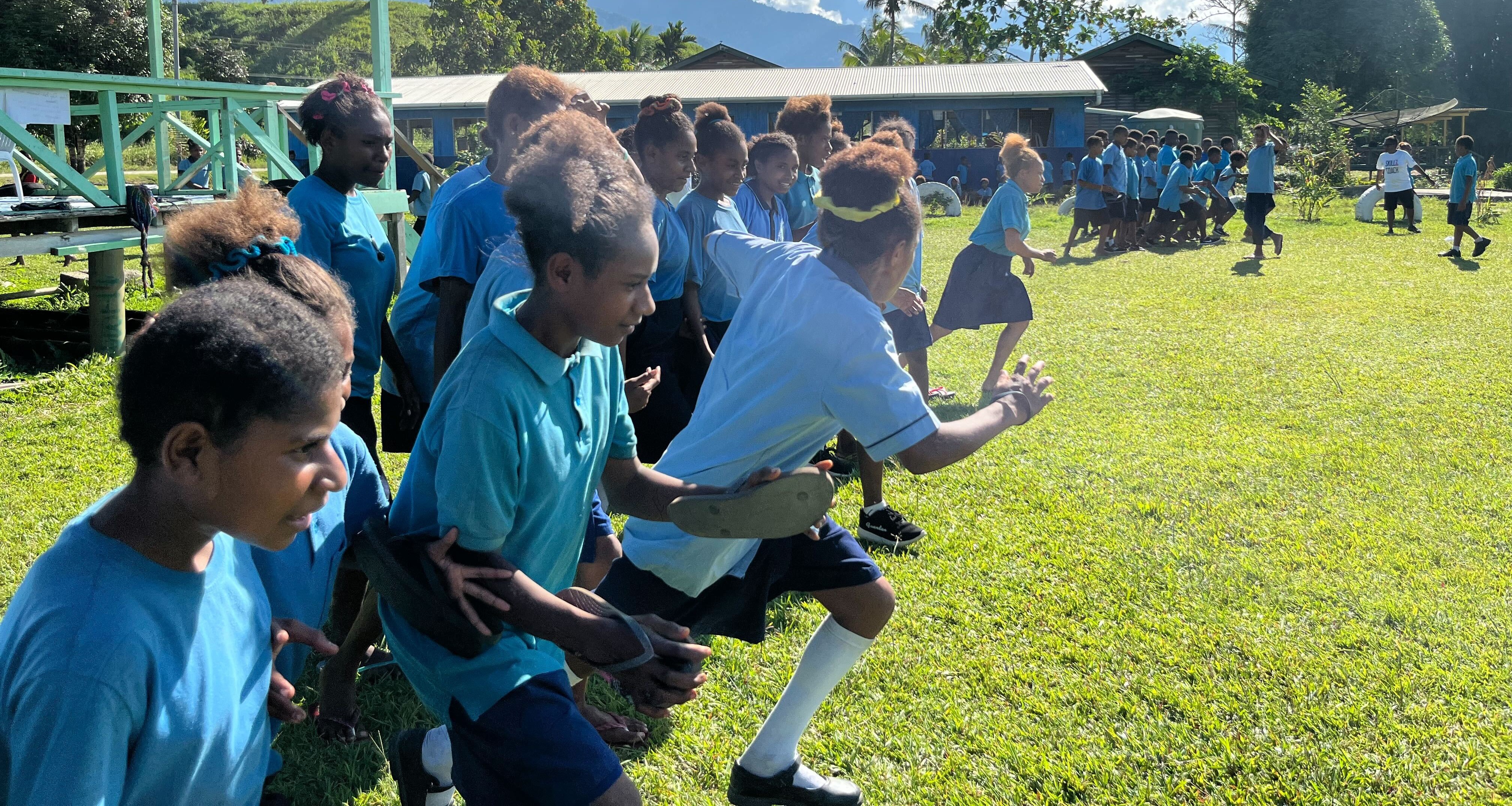 A line of K4K participants charging down a sports field
