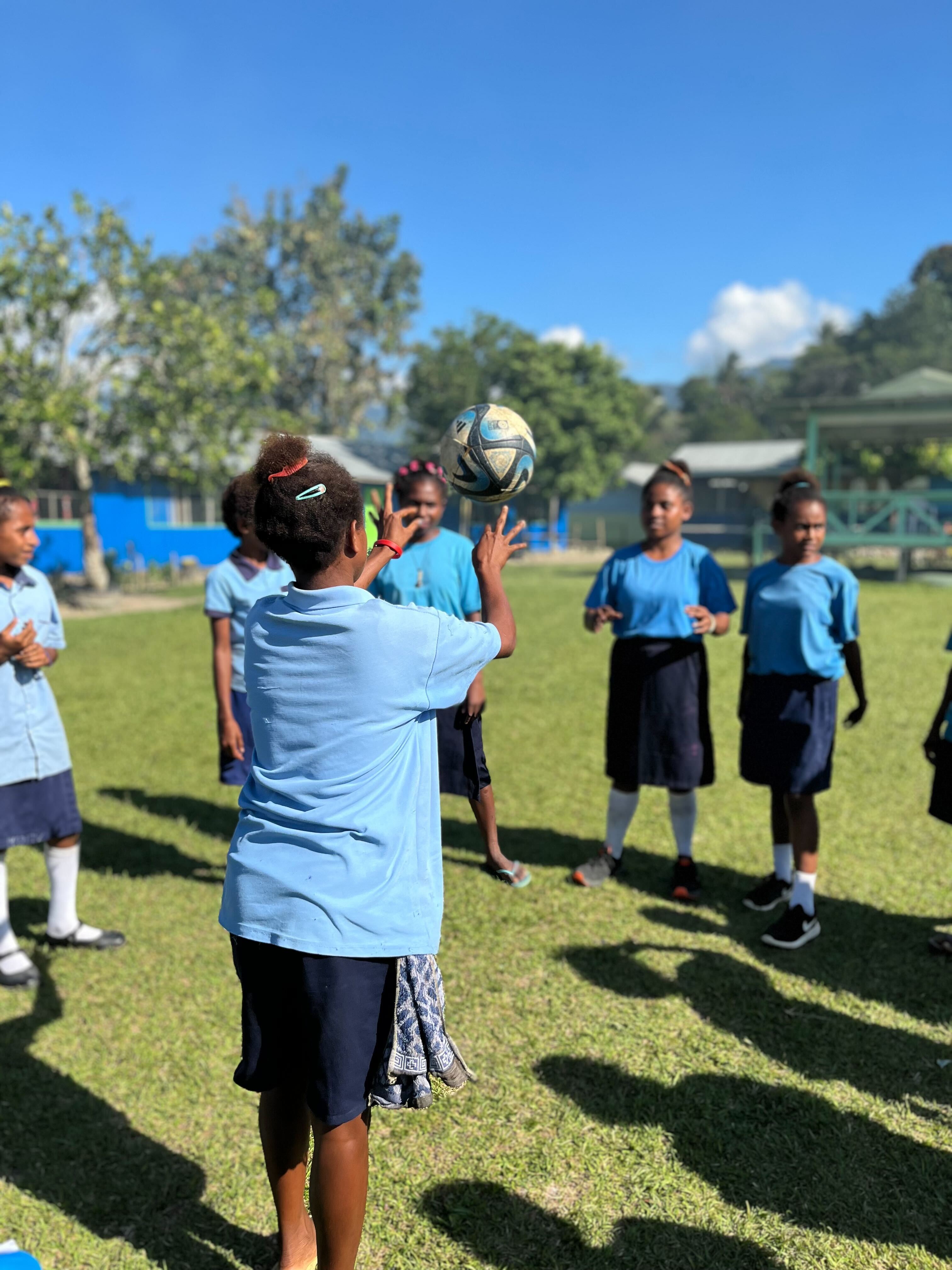 A female K4K participant throwing a soccer ball to a group of K4K participants